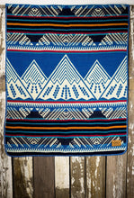 Load image into Gallery viewer, Pictured is an ocean blue, red, black, orange, sky blue and white coloured, mountain patterned baby blanket. This is the Heartprint Threads 'Baby Expeditions' Baby Blanket, created by Ecuadorian Artisans. Perfect for your everyday soft & warm baby blanket needs! Available for sale at SMRT Tent in Edmonton, Canada.