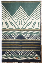 Load image into Gallery viewer, Pictured is a green, white & dark blue, mountain-patterned and laid-out blanket. This is the Heartprint Threads 'Tracing the Columbia' Mountain Flakes Line Queen Blanket, created by Ecuadorian Artisans. Throw this warm blanket over your sleeping bag while camping outdoors! Available for sale at SMRT Tent in Edmonton, Canada.