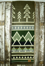 Load image into Gallery viewer, Pictured is a green, patterned and laid-out blanket. This is the Heartprint Threads 'Ponderosa' Tree Line Queen Blanket, created by Ecuadorian Artisans. Throw this warm blanket over your sleeping bag while camping outdoors! Available for sale at SMRT Tent in Edmonton, Canada.