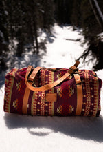 Load image into Gallery viewer, Pictured is a dark red, cherry red, cream, light brown, orange, burgundy, beige and dark golden-yellowish tan patterned bag (similar looking to a duffle bag) with soft, orangey-brown leather straps. This is the Heartprint Threads 'Okanagan 2.0' Weekend Traveller Bag, created by Ecuadorian Artisans. Perfect for all your week-long packing, storing and travelling needs! Available for sale at SMRT Tent in Edmonton, Canada.