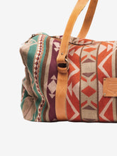 Load image into Gallery viewer, Pictured is a maroon, light tan, beige, brown, dark reddish brown, cream, teal, and orange patterned bag (similar looking to a duffle bag) with soft, orangey-brown leather straps. This is the Heartprint Threads 'Two Jack' Weekend Traveller Bag, created by Ecuadorian Artisans. Perfect for all your week-long packing, storing and travelling needs! Available for sale at SMRT Tent in Edmonton, Canada.
