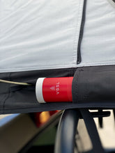 Load image into Gallery viewer, Pictured is a close-up view of an outside side pocket from a light grey, completely set-up softshell roof top tent. This is “The” Softshell, a roof top tent perfect for all overland roof top tent family outdoor camping! Available for sale by SMRT Tent in Edmonton, Canada.