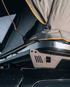 Pictured in a close-up is a supporting strut of a completely set-up hard shell roof top tent in Grey. The close shot allows a clearer view of the outside supports that lets this tent have extreme ease of access and quick set-up and pack-up times. This is the medium-sized Sky Loft, a 2-person hard shell roof top tent perfect for all overland roof top tent family outdoor camping! Available for sale by SMRT Tent in Edmonton, Canada.