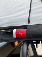 Load image into Gallery viewer, Pictured is a close-up view of an outside side pocket from a light grey, completely set-up softshell roof top tent. This is “The” Softshell, a roof top tent perfect for all overland roof top tent family outdoor camping! Available for sale by SMRT Tent in Edmonton, Canada.
