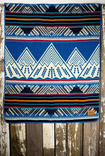 Load image into Gallery viewer, Pictured is an ocean blue, red, black, orange, sky blue and white coloured, mountain patterned baby blanket. This is the Heartprint Threads &#39;Baby Expeditions&#39; Baby Blanket, created by Ecuadorian Artisans. Perfect for your everyday soft &amp; warm baby blanket needs! Available for sale at SMRT Tent in Edmonton, Canada.
