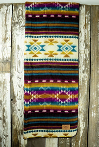 Pictured is a technicolour, patterned and laid-out blanket. This is the Heartprint Threads ‘Colourful Minds’ Aztec Series Double Blanket, created by Ecuadorian Artisans. Throw this warm blanket over your sleeping bag while camping outdoors! Available for sale at SMRT Tent in Edmonton, Canada.