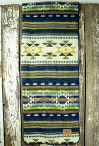 Pictured is a green & blue, patterned and laid-out blanket. This is the Heartprint Threads ‘Shape of Water’ Aztec Series Double Blanket, created by Ecuadorian Artisans. Throw this warm blanket over your sleeping bag while camping outdoors! Available for sale at SMRT Tent in Edmonton, Canada.
