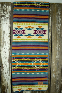 Pictured is a rainbow-coloured, patterned and laid-out blanket. This is the Heartprint Threads ‘Stardust’ Aztec Series Double Blanket, created by Ecuadorian Artisans. Throw this warm blanket over your sleeping bag while camping outdoors! Available for sale at SMRT Tent in Edmonton, Canada.