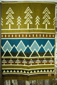 Pictured is a patterned and laid-out blanket. This is the Heartprint Threads 'Limber' Tree Line Queen Blanket, created by Ecuadorian Artisans.  Throw this warm blanket over your sleeping bag while camping outdoors! Available for sale at SMRT Tent in Edmonton, Canada.