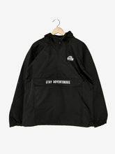 Load image into Gallery viewer, Pictured is the front of a Black drawstring anorak/rain jacket with the a SMRT Tent logo printed over the upper-left chest area in white and the words Stay Adventurous also in white printed across the front multi-pocket flap. Layer around your SMRT Tent roof top tent camp in this sweet SMRT Tent Rainy Jacket! Available for sale by SMRT Tent in Edmonton, Canada.
