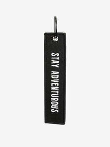 Pictured is a black, simple ring keychain with the words Stay Adventurous stitched in white on a black strip of sturdy fabric. Perfect for any roof top tent camping or hiking enthusiast! Available for purchase by SMRT Tent in Edmonton, Canada.